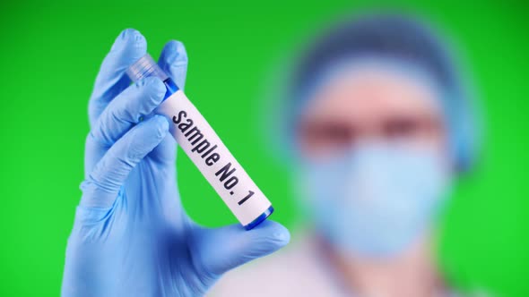 Green Background. Close-up, Doctor's Hand in Blue Medical Glove Holds Test Tube with Sample