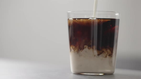 Slow Motion Pour Cream in Cola in Tumbler Glass on Concrete Countertop with Copy Space