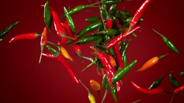 Super Slow Motion Shot of Mixed Chilli Side Collision on Dark Red Background at 1000Fps.