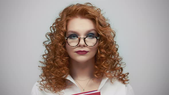 Woman in Glasses Standing in Studio. Portrait of Female Student Holding Book