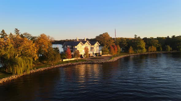 Cinematic aerial view of a Lake House, luxurious property real state facing a wonderful sunset