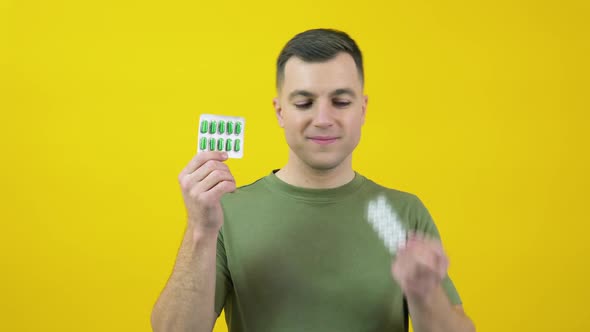 A Man in Holds Two Plates of Different Pills in His Hands and Expresses Confusion