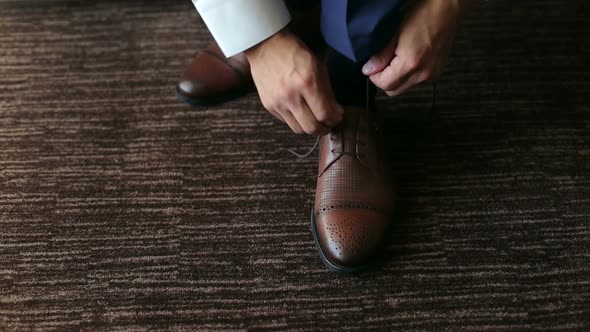 Man Ties Up Shoelaces on Brown Leather Shoes