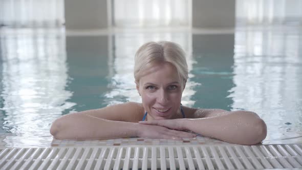 Blond Smiling Woman Posing at Poolside. Portrait of Happy Young Caucasian Lady Resting in Spa in