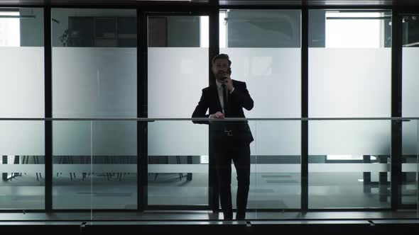 Silhouette of a Businessman That is Talking at Phone Inside the Business Building