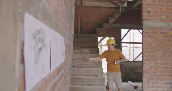 Construction Worker Using A Measuring Tape In Unfinished Brick House
