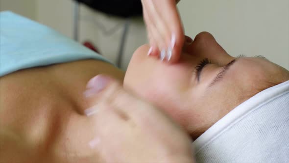 Massage Therapist Cosmetologist Makes Cheeks Massage for Woman in Beauty Salon