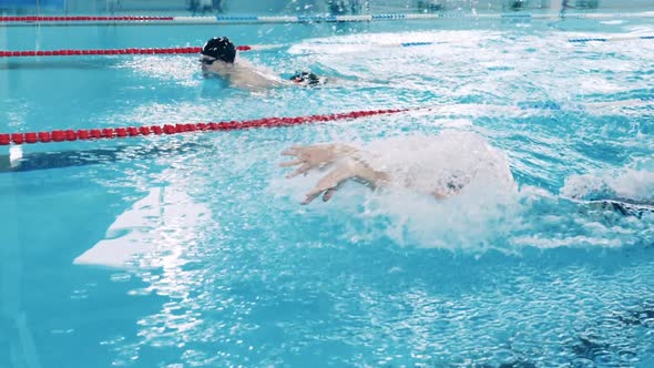 Slow Motion of Two Butterfly Swimmers Crossing the Pool