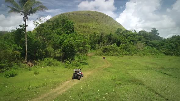 Aerial view two quadricycles doing trail next Chocolate Hills Complex, Batuan.