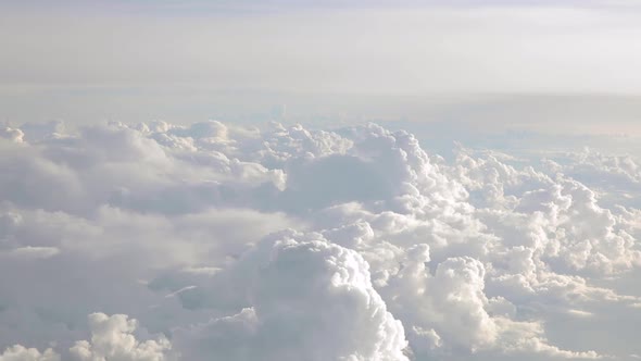 Airplane flying above clouds with a blue sky over the horizon