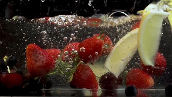 Bunch of different fruits fall in tank full of water and creating bubbles