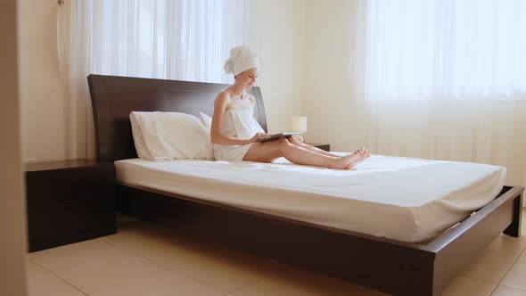 Woman in Bath Towel Using Laptop on Bed of Hotel Room