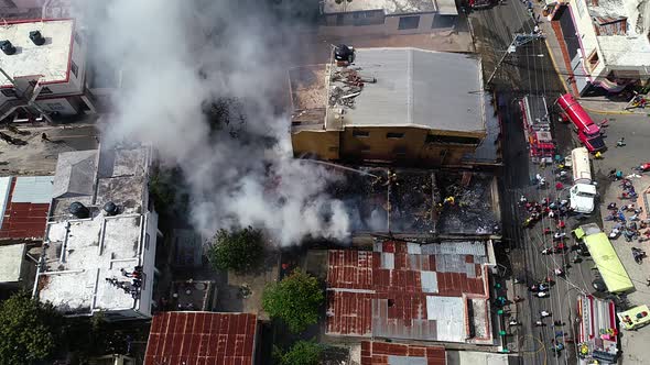 Aerial view above a smoking building, firefighters trying to control the fire, in ghetto Favela, Rio