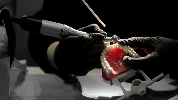 Close-up of a Dentist Practicing on a Mock-up of a Skeleton of Teeth Using a Drill Machine. the