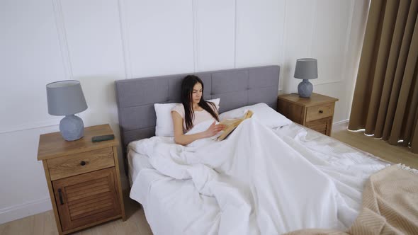 Woman Reading A Book On Bed