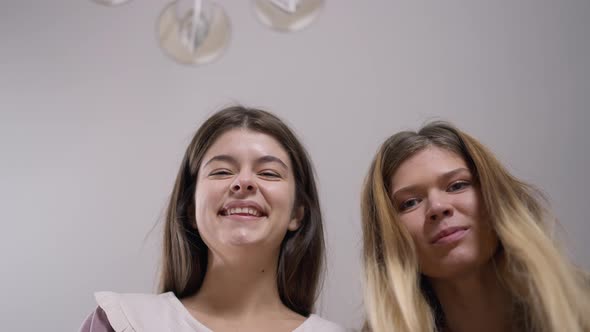 Closeup Two Cheerful Women Looking at Camera Laughing Out Loud with Ceiling at Background