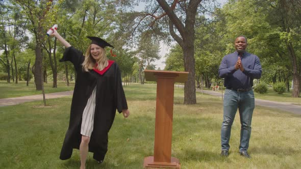 Excited Lovely Female Graduate Celebrating Receiving University Degree at Graduation Day