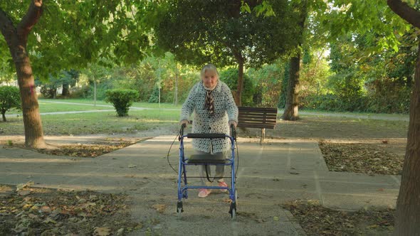 Grandma Walks Using Wheelchairwalker in Autumn Park