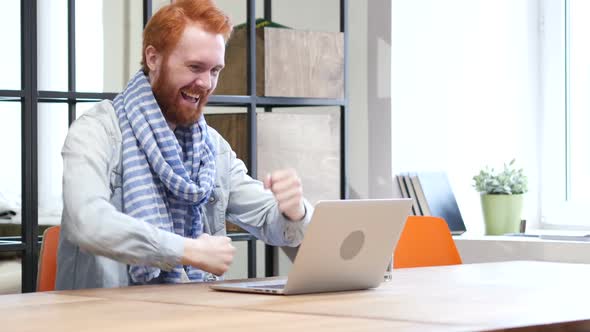 Beard Man Celebrating Success while Working on Laptop