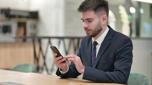 Young Businessman Using Smartphone in Office