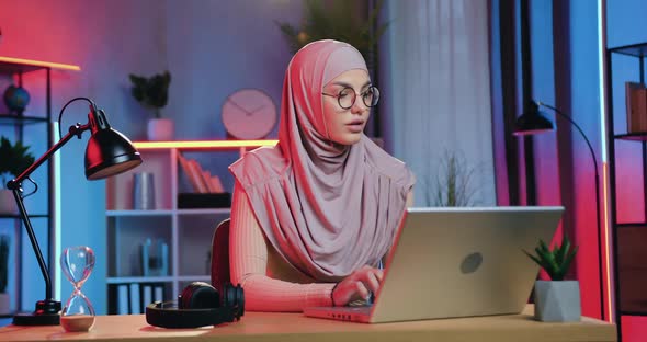 Girl in Headscarf in Glasses Working on Computer at the Workplace in Home Office in the Evening