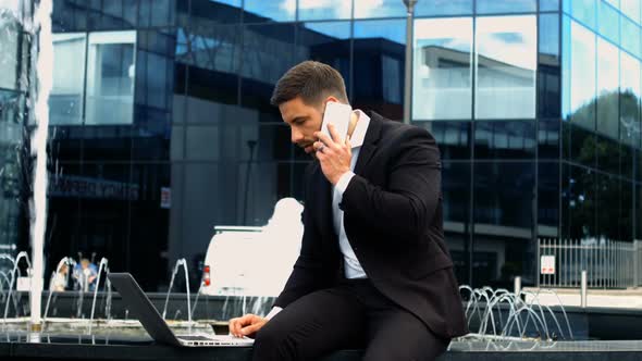 Businessman using laptop while talking on phone