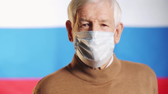 Portrait of Elderly Man in Medical Mask on Russian Flag