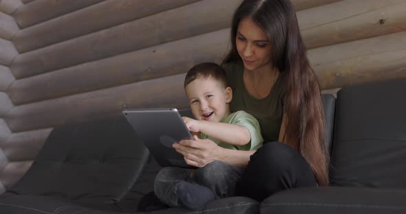 Modern Technology in Family Relationships Happy Kid with Mom is Played with Digital Tablet in