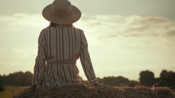 Young woman in hat resting on a haystack