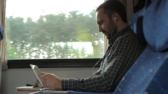 Serious man watching news on a tablet in a train.