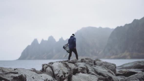 Hiker Removing Backpack Fjord Rocks