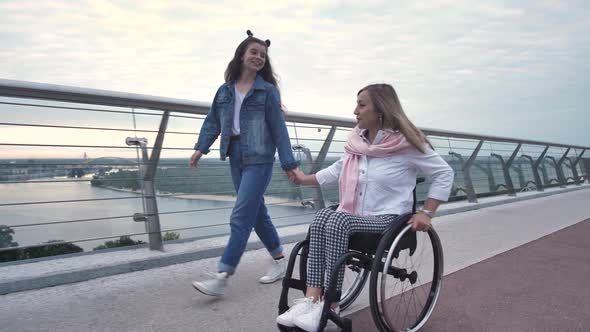 Happy Mom on Wheelchair During Walk with Daughter