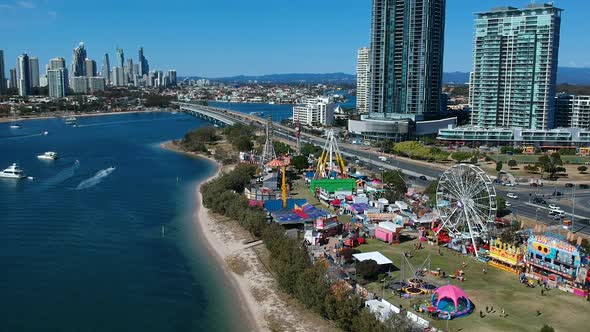 Aerial view of a colourful carnival situated by the sea with a city skyline in the background