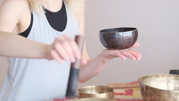 Woman Playing on Tibetan Singing Bowl While Sitting on Yoga Mat