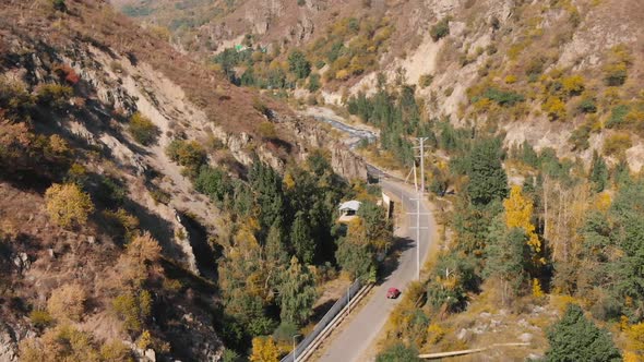 Aerial View of Road with Red Car in Autumn Mountain Forest