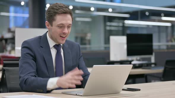 Businessman Celebrating Success While Using Laptop in Office