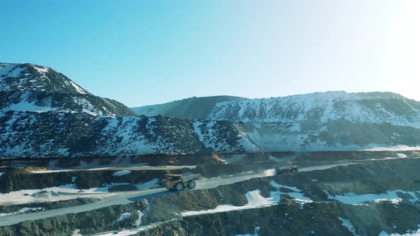 Opencast Mine with Two Trucks Riding Along Its Road