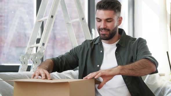 Man with Adhesive Tape Gun Packing Box at Home