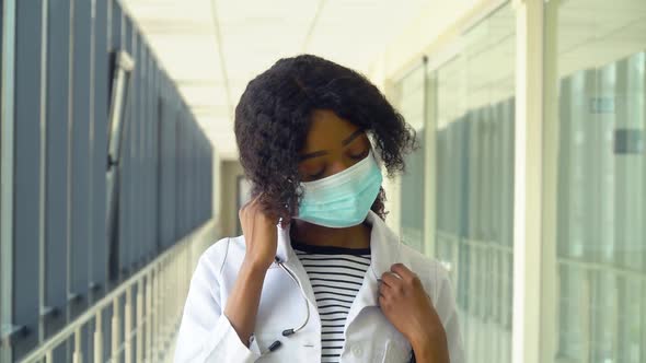 African American Female Doctor Removes a Medical Mask in Modern Clinic. End of Quarantine. Stop