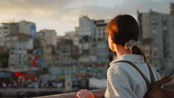 Traveling woman with a backpack looking at the flying seagulls from the bridge