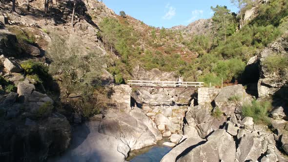 Senior Couple on Mountain Bridge over River Rocks