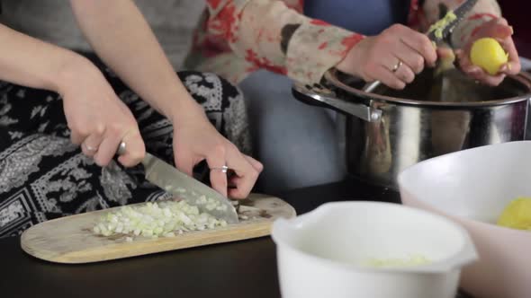 Women prepare dinner. Slicing fresh onion and peeling boiled potato