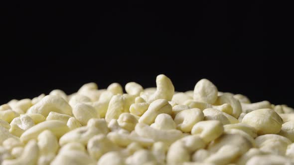 A Handful of Fresh Cashews Rotate on a Black Background