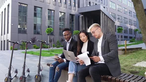 Positive Successful Mixed Race Young People which Sitting on the Bench Near Urban Building