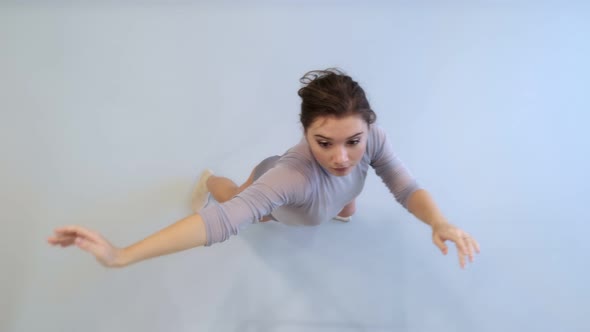 The girl dances a modern dance in a bright studio. Slow and smooth movement. View from above.