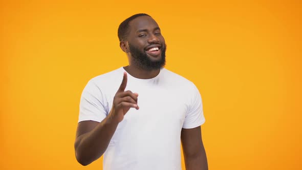 Smug Afro-American Man Pointing His Finger Knowingly Against Yellow Background