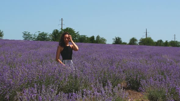 Beautiful woman is sitting in a lavender field. Lavender scent of beautiful flowers.