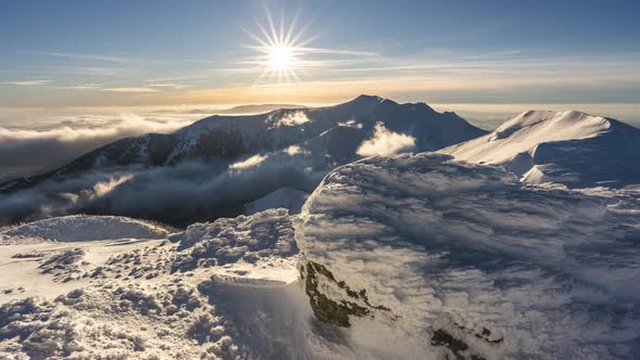 Frozen Alps Mountains with Misty Clouds Motion Fast in Valley in Sunny Evening