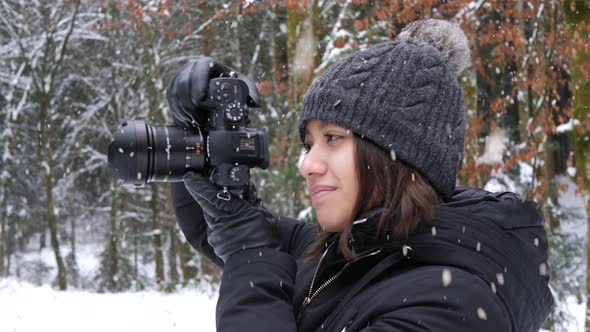 Beautiful female take photos of snowfall in forestry area, close up view
