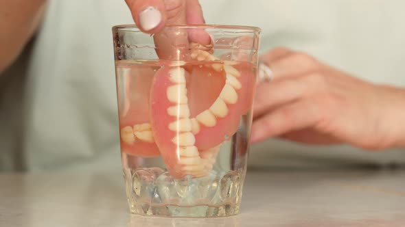 A woman takes out and puts on removable dentures.